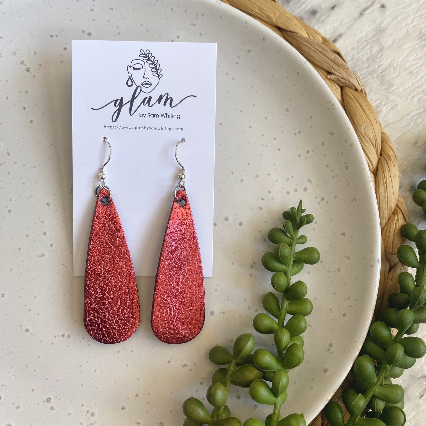 Metallic maroon droplet leather earrings on a silver coloured hook.