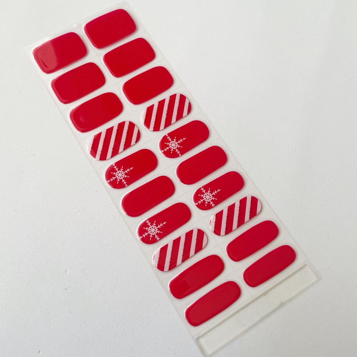 Sheet of red nail stickers with snowflake and candy cane designs on a white background