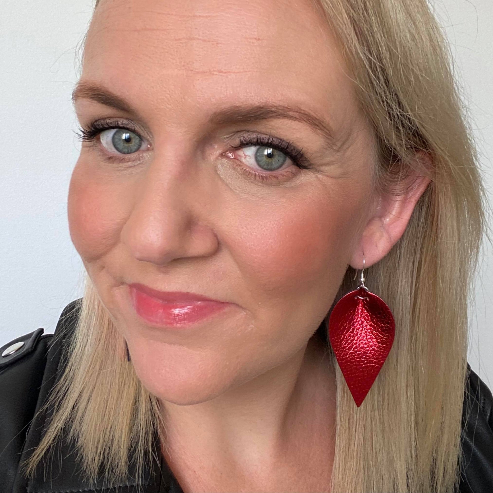 Selfie of Red metallic petal earrings. Faux leather with silver coloured hooks.