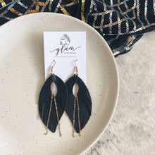 Load image into Gallery viewer, Black feather leather earrings with gold chain on a golden coloured hook.
