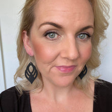 Load image into Gallery viewer, Black ornate cut out leather earrings with a silver coloured hook. selfie
