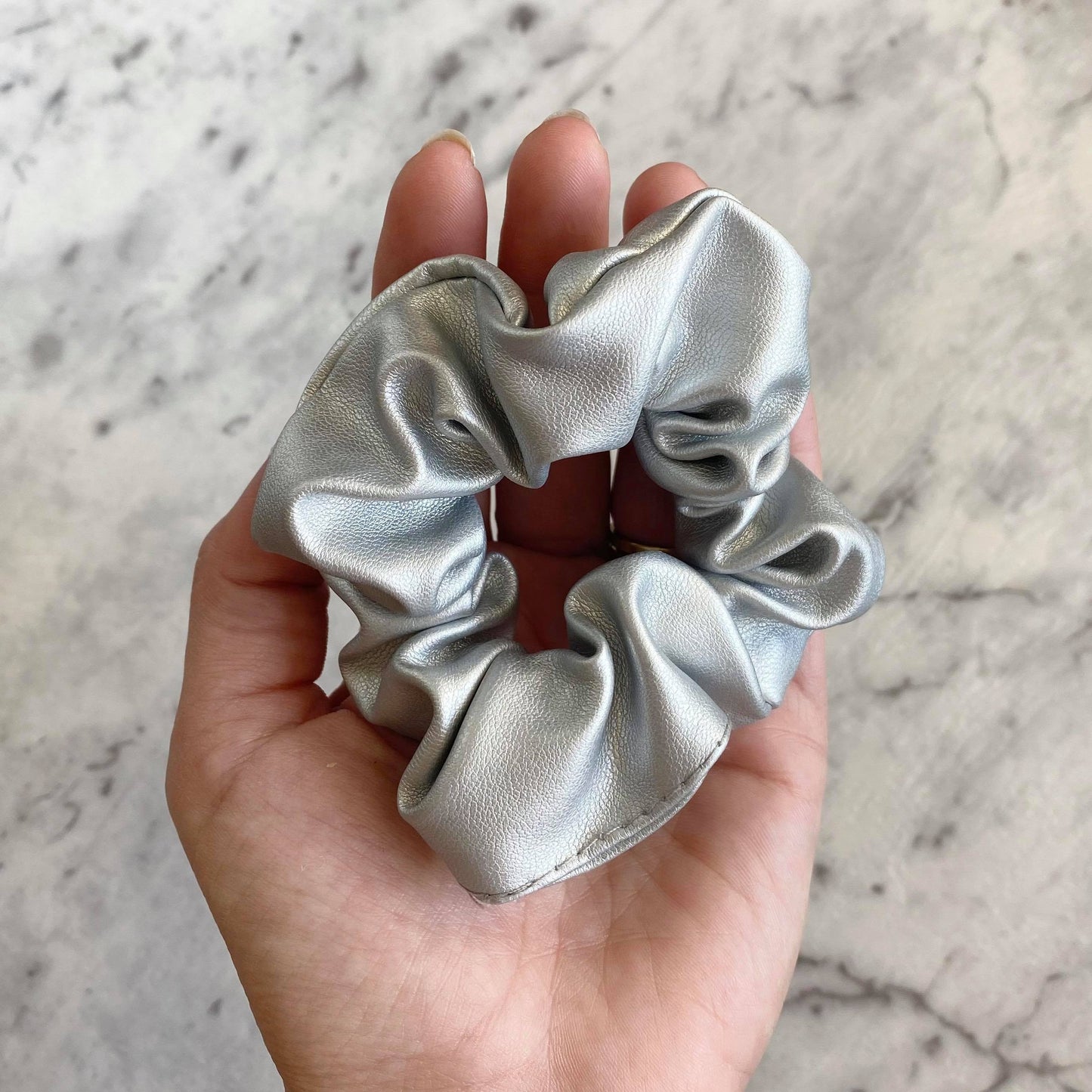 Silver faux leather hair scrunchie in a hand