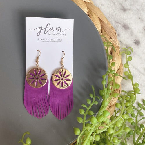 purple fringe leather earrings featuring a gold coloured embellishment and hook